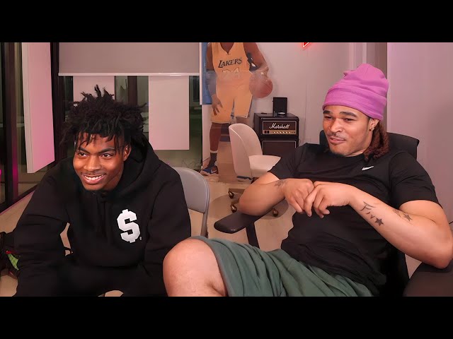 Still from a PlaqueBoyMax streaming session — two artists seated in a home studio, one in a black hoodie and one in a pink beanie