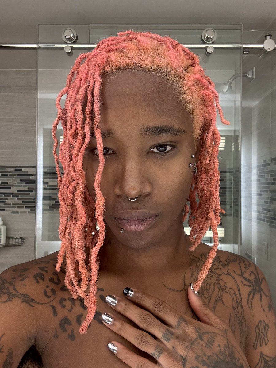 Nine Vicious portrait — peach-pink dreads, septum and lip piercings
